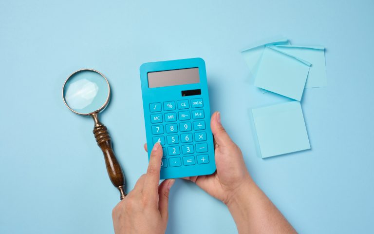 Magnifier and calculator on a blue background, budget calculation. View from above